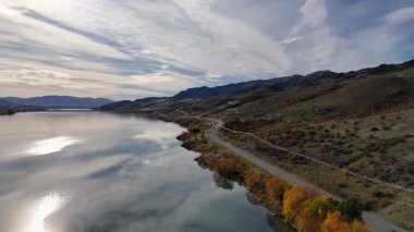 Dunstan Gölü 'nün çevresini çevreleyen hava manzarası, dramatik bir gökyüzü altında yolları ve sonbahar yapraklarını gözler önüne seriyor.