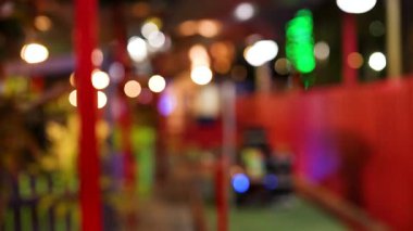 Renkli bir minyatür golf sahasının bulanık görüntüsü. Parlak bir ışık ve canlı bir atmosferi var.