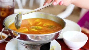 Birisi canlı bir Yengeç ortamında metal bir tencerede sıcak Tayland çorbası servis ediyor, yerel mutfak kültürü sergiliyor.