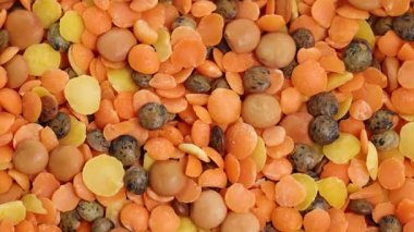 Mercimek, fasulye ve tohumların canlı bir karışımı dinamik bir şekilde döner, zengin dokular ve renkler yakın çekim görüntüsünde sergilenir.