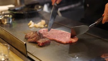 Şef ızgarada biftek ve sebzeleri ustalıkla pişirir.