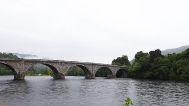 Sakin bir nehir boyunca uzanan taş köprü