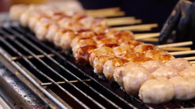 Bangkok caddesindeki markette sosisler ızgara yapıyor.