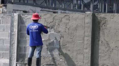 Bir inşaat işçisi duvara alçı yapıştırır..