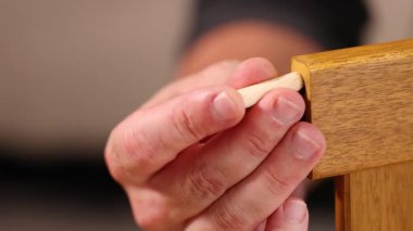 Eller mobilyalara tahta bir çivi takar ve çekiçle sabitler. Yakın çekim hassasiyeti ve işçiliği vurgular