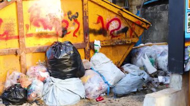 Tayland, Phuket 'te, çöp torbaları ve dağınık döküntülerle dolu dağınık bir çöplük. Parlak gün ışığı kentsel bozulmayı vurguluyor