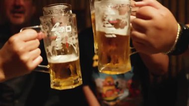 Arkadaşlar kutlama için bira bardaklarını tokuşturuyor.