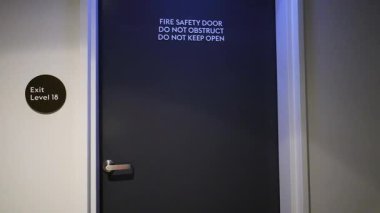 Modern tasarım ve yangın güvenlik levhası ile loş ışıklı bir apartman koridoru, pürüzsüz bir kamera tavasına kaydedildi.