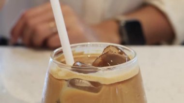 Buzlu kahveyi pipetle karıştırıyorum.