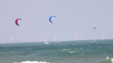 Uçurtma sörfçüleri dalgalı okyanus dalgalarında süzülür