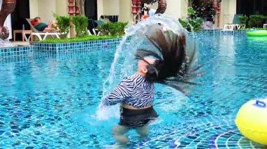 Bir insan neşeli bir şekilde saçlarını dalgalı bir yüzme havuzunda çevirir. Tayland, Krabi 'de parlak gün ışığında dinamik su sıçratır.