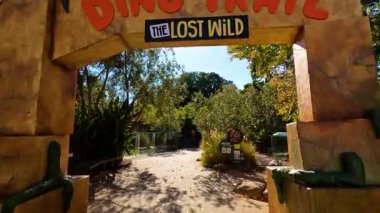 Melbourne Hayvanat Bahçesi 'nde dinozor temalı patikada yürüyen ziyaretçiler