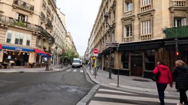 Kalabalık bir Paris caddesinde yürüyen iki kişi.