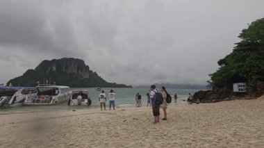 Turistler Tayland 'da bulutlu bir plajın keyfini çıkarırlar.