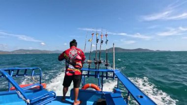 Tayland, Phuket 'te, açık gökyüzünün altında canlı okyanus dalgalarıyla bir kişi balık tutuyor.