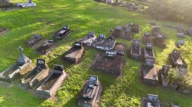 İnsansız hava aracı görüntüleri, ılık, altın güneş ışığı altındaki mezar taşlarıyla huzurlu bir mezarlık manzarası yakalıyor.