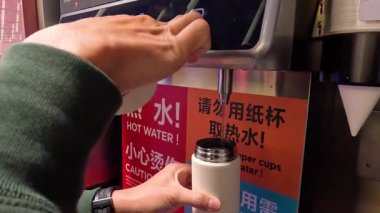 İnsan sıcak su bidonundan şişeyi doldurur.