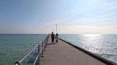 Güneşli bir iskelede gezinen bir çift