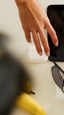 Eller çabucak muz, güneş gözlüğü ve beyaz bir masadan su şişesi gibi şeyleri toplar.