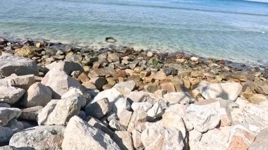 Sakin okyanus dalgaları Kalim Sahili, Phuket 'te parlak güneş ışığı altında kayalık kıyılara doğru yavaşça süzülüyor.