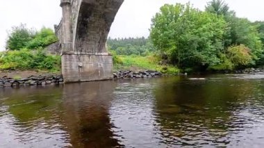 Sakin bir nehir tarihi bir köprünün altından akıyor
