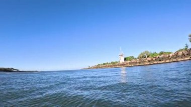 Açık mavi gökyüzünün altında deniz feneri ve kıyı şeridi