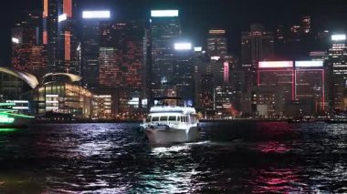 Bir tekne aydınlatılmış şehir manzarasına doğru ilerliyor.