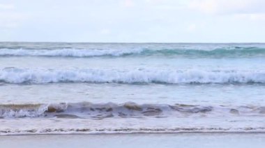 Okyanus dalgaları kumlu bir kıyıya vuruyor.