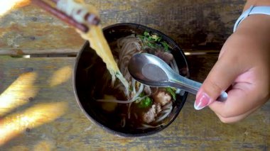 Yemek çubuğu ve kaşıkla erişteyi seven kişi