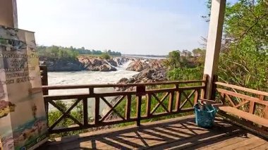 Champasak, Laos 'taki ahşap bir gözcüden sakin bir şelale manzarası. Parlak gün ışığı doğal güzelliği ve sükuneti arttırır.