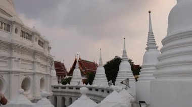 Bangkok 'taki Wat Prayurawongsawat' ın sakin bir sahnesinde bulutlu bir gökyüzü altında ikonik beyaz şoklarını sergiliyor.