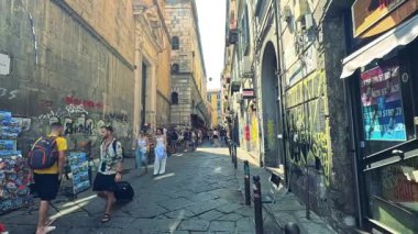 İnsanlar canlı, duvar yazısıyla dolu bir sokakta yürüyorlar.