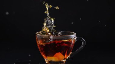 Bir küp şeker çay bardağına düşer ve siyah arka planda bir sıçrama yaratır. Yüksek hızlı fotoğrafçılıkta yakalandı