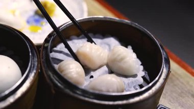 Yemek çubukları buharlı tencereden karides köftesi topluyor.