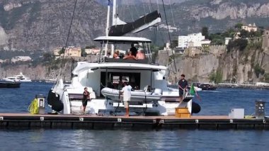 İnsanlar Sorrento rıhtımına bir tekne yanaştırıyor.