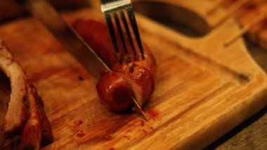 Çatal ve bıçakla sıralı sosis kesimi.