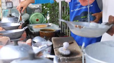 Canlı sokak sahneleri Phuket 'te geleneksel Tayland hindistan cevizi atıştırmalıkları hazırlarken el ele tutuşuyor. Parlak ışıklandırma hareketli pazar atmosferini vurguluyor