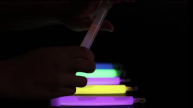 Karanlıkta parlayan çubukları düzenleyen eller