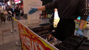 Sokak satıcısı Japon bozuk para krepleri hazırlıyor.