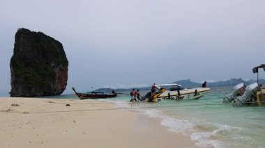 Sahilden kayalık manzaralı bir tekne ayrılıyor.