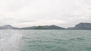 Dalgalar uzak dağların yakınındaki bir tekneye çarpıyor