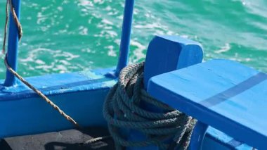 Sarmalı halatı olan mavi bir balıkçı teknesi Tayland, Phuket 'te parlak güneş ışığı altında canlı turkuaz sularda yüzer.