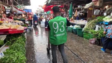 Yeşil gömlekli adam kalabalık pazarda yürüyor.