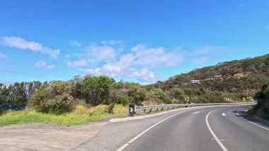 Büyük Okyanus Yolu 'nda bir sürücüyü görüntüleyen 45 saniyelik bir video. Virajlı yollar, yemyeşil alanlar ve açık gökyüzünün altındaki kıyı manzarası.