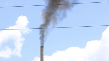 Uzun bir bacadan ağır dumanlar çıkıyor.