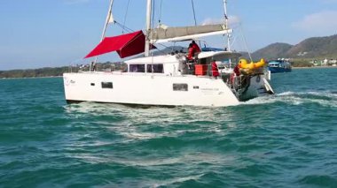 Bir yat canlı Phuket sularında yüzüyor, dingin okyanus manzaraları ve dinamik hareketler sergiliyor berrak gökyüzü altında