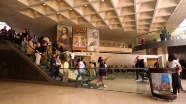 Ziyaretçiler etrafta dolaşıp resimleri inceliyor.