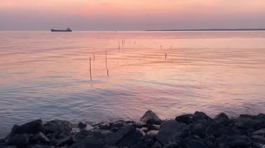 Sakin deniz ve kayalarla sakin gün batımı manzarası