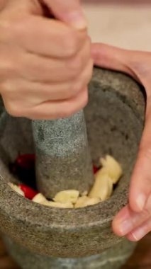 Eller sarımsak ve biber ezer taş bir havanda, canlı, aromatik bir macun yaratır.