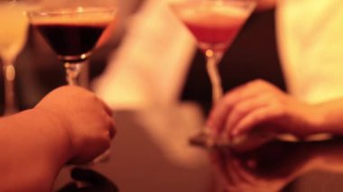 Masadaki kokteyllere uzanan iki el.